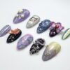 Almond press-on nails from the opposite side, with silver cross charms, pearls, striped nails and a pale yellow gradient