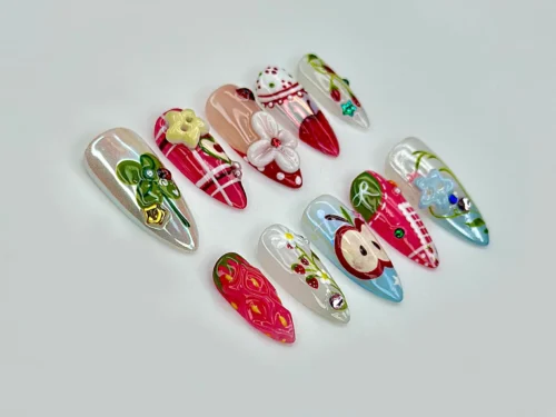 Red gingham and fruit press-on nails laid flat: a 3D apple, strawberry, clover, cherries and small flowers