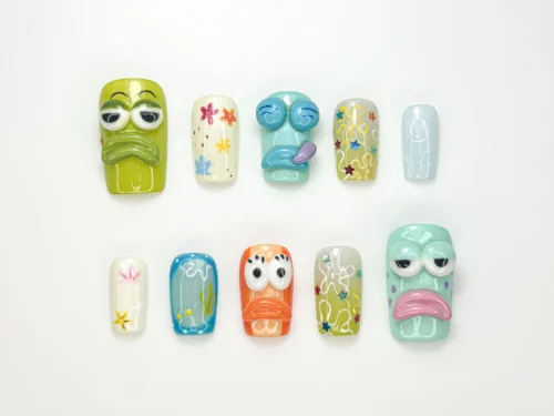 Straight-on view of the sea cartoon press-on nails: a grumpy green face, a mint face with pink lips and pale blue nails