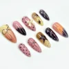 Almond press-on nails from another angle: yellow to black fades, pink dotted nails, a brown star and a pearl on a black tip
