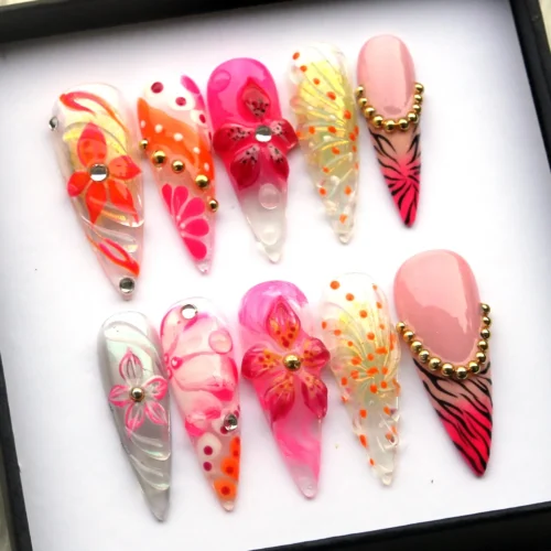 Orchid press-on nails in a black-edged box from another angle: neon pink and orange flowers and gold bead chains
