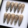 Champagne shimmer stiletto press-on nails flat on white, with silver chrome vines, net textures, clear gems and drop domes