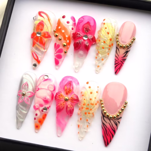 Neon orchid stiletto press-on nails in a box, with a 3D pink orchid, orange flowers, gold beads and tiger-stripe tips