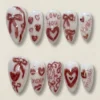 Milky white almond press on nails hand-lettered LOVE YOU, XOXO and mwah with red bows, hearts, lips and pearls