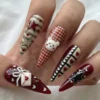Dark red and cream stiletto press-on nails worn on a hand, with a 3D bow envelope, gingham teddy bear and hearts