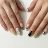 Nude almond press-on nails worn on both hands, with painted cats, polka dots, piano keys and chrome tips