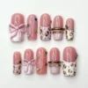 Blush pink square press on nails with 3D pink bows, gold leopard spots on white tips and a gem-set gold band