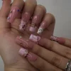 Long pink press-on nails worn on a hand with silver rings, with 3D bows, leopard-print tips and tiny gems