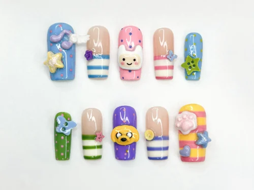 Flat lay of ten square press-on nails with striped tips, 3D star charms, a yellow dog face and a white-hooded face