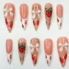 Sheer pink stiletto press on nails with white French tips, painted strawberries and 3D white bows with pearls