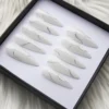 Ten milky white stiletto press-on nails in a black box, each with one thin silver glitter swirl line