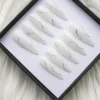 Milky white press-on nails in a black box from another angle, a wavy silver glitter line on every nail