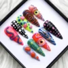 Psychedelic stiletto press-on nails in a box on white fur, with 3D eyeballs, spirals, polka dots and mushrooms