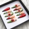 Angled view of ladybug press-on nails: raised red ladybugs on green, white daisies and black-veined red wing nails