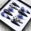 Angled view of navy ombré press-on nails showing a gold-edged cat-eye nail, spotted nails, crystals and a blue flower