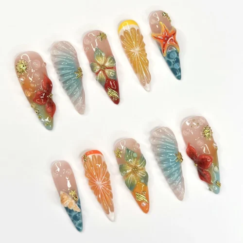 Citrus and shell press-on nails from another angle, with an orange slice, green plumeria, red hibiscus and a starfish tip