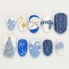 Blue Christmas sweater press-on nails in cobalt and white with 3D cable knit, a snowman, a striped scarf and a tree