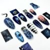 Navy and pale blue almond press-on nails beside small printed scene cards, with gothic portraits and black-and-white stripes
