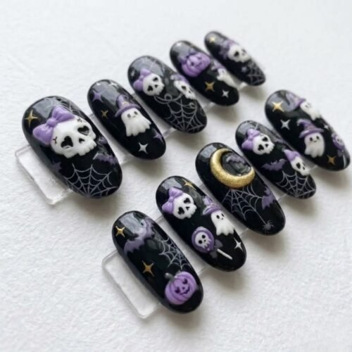 Angled view of black Halloween press-on nails with a large skull in a purple bow, cobwebs and a gold crescent moon