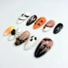 Playful candy corn press-on nails and a graveyard gleaming in the moonlight.