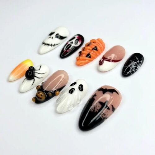 Playful candy corn press-on nails and a graveyard gleaming in the moonlight.