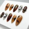 Orange-base press-on nails with a spiderweb pattern.