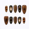 Ghosts and spiderwebs press-on nails in amber glitter and black with ghosts and cats in gold frames, bats and stripes