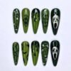 Skulls and bats press-on nails in olive and forest green with white skull masks, dark drips, stitches and silver stars