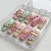 Pastel coffin press-on nails in a clear case, with 3D gingerbread men, a candy cane, a Christmas stocking and a star charm