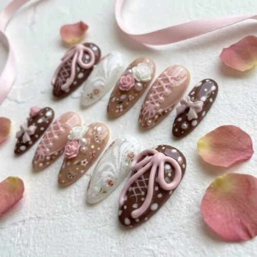 Chocolate brown and nude pink almond press-on nails among rose petals, with big 3D pink bows, white lace and polka dots