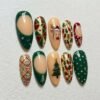 Almond press-on nails in pine green, red and cream with a reindeer face, a tree, string lights, hearts and green French tips