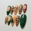 Polka-dot patterned press-on nails on a Christmas green background.