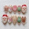 Christmas cookie press-on nails in blush and pink with 3D Santas, snowmen in pink scarves, a reindeer and gold snowflakes