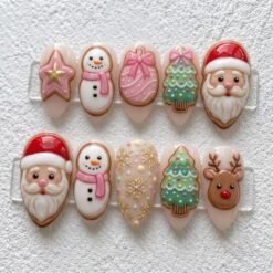 Christmas cookie press-on nails in blush and pink with 3D Santas, snowmen in pink scarves, a reindeer and gold snowflakes