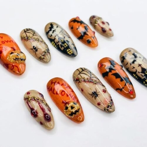 Almond press-on nails in orange, beige and black with cobwebs and spiders, bats, a gold skull charm and handwritten lettering