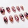 Press-on nails featuring a sparkly pink base and pumpkin designs.