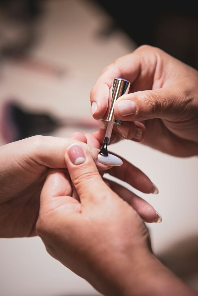 Close-up of hands carefully painting a nail with a fine brush