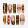 Amber gemstone press-on nails with olive and blush bases, gold scrollwork, oval jewel-like details and crystal-like accents.