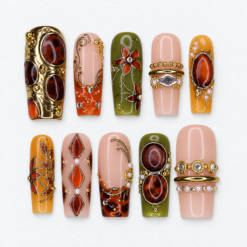 Amber gemstone press-on nails with olive and blush bases, gold scrollwork, oval jewel-like details and crystal-like accents.