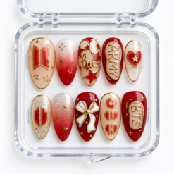 BTS fan-inspired press-on nails in red, cream and gold with ARMY text, stars, a heart, bow and glitter accents