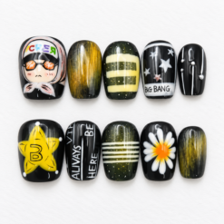 Ten black and olive press-on nails with yellow accents, white stars, striped and marbled patterns, a daisy, an illustrated character and fan-style lettering.