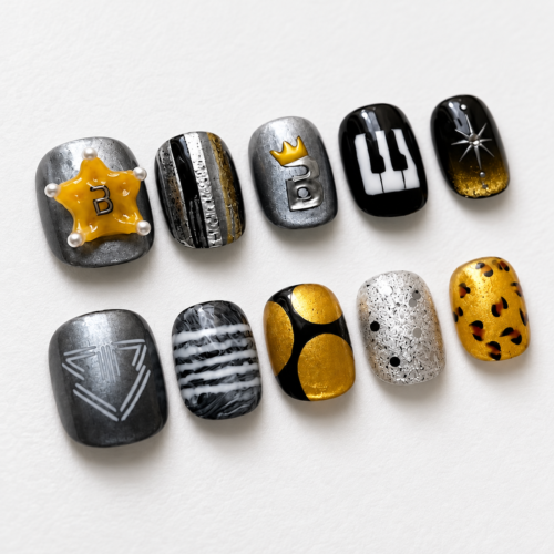 press-on nails featuring piano keys, a crown, a raised letter