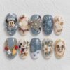 Blue winter press-on nails with snowflakes, festive florals, gold accents and mouse-character designs.
