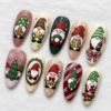 Diagonal view of Christmas press-on nails with gnomes, Christmas trees, snowflakes, bows, and bells on white linen