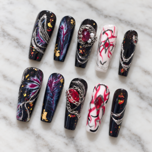 midnight nebula press-on nails with starry black tips, blue-magenta swirls, gold flecks, silver chains and red gems