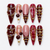 Burgundy ruby press-on nails with blush accents, gold frames, pearl-like beads, chains and ornate jewel details