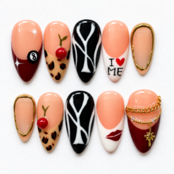 Press on nails with cherry and eight-ball art, leopard tips, burgundy accents, and gold-tone charms.