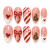 Pink christmas press-on nails with a red bow, candy-cane stripes, a decorated tree, gold stars and French tips
