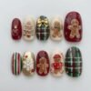 Christmas gingerbread press-on nails in red, cream and green plaid with gingerbread men, a gold bow and a white snowflake
