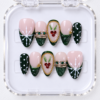 press-on nails with forest green tips, white snowflakes, red gem berries, and gold-tone frames.